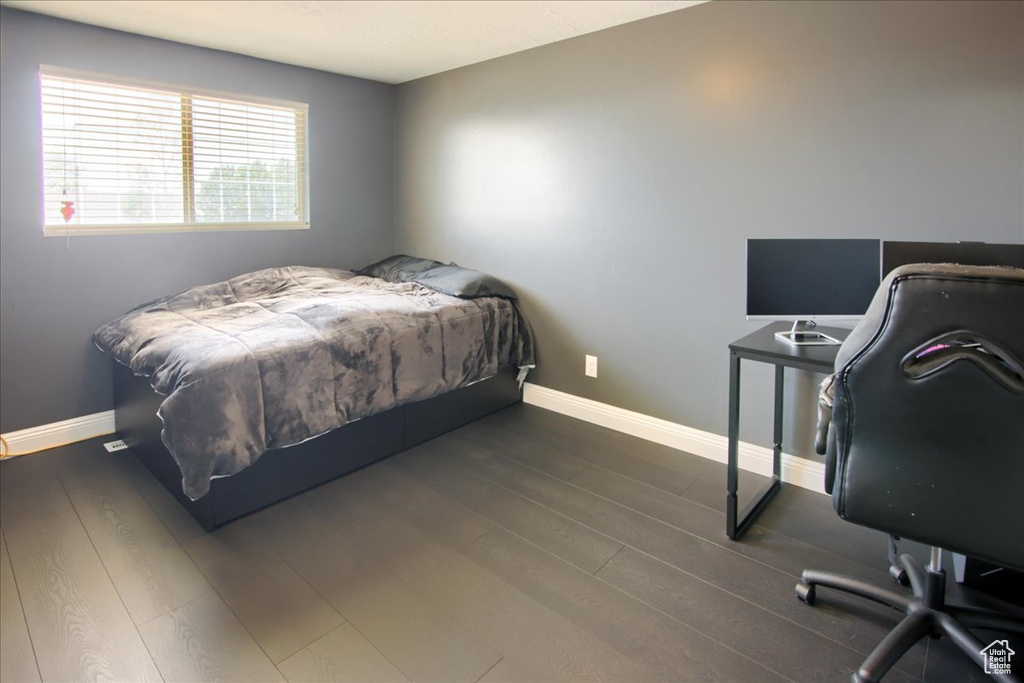 Bedroom with wood finished floors, an office area, and baseboards