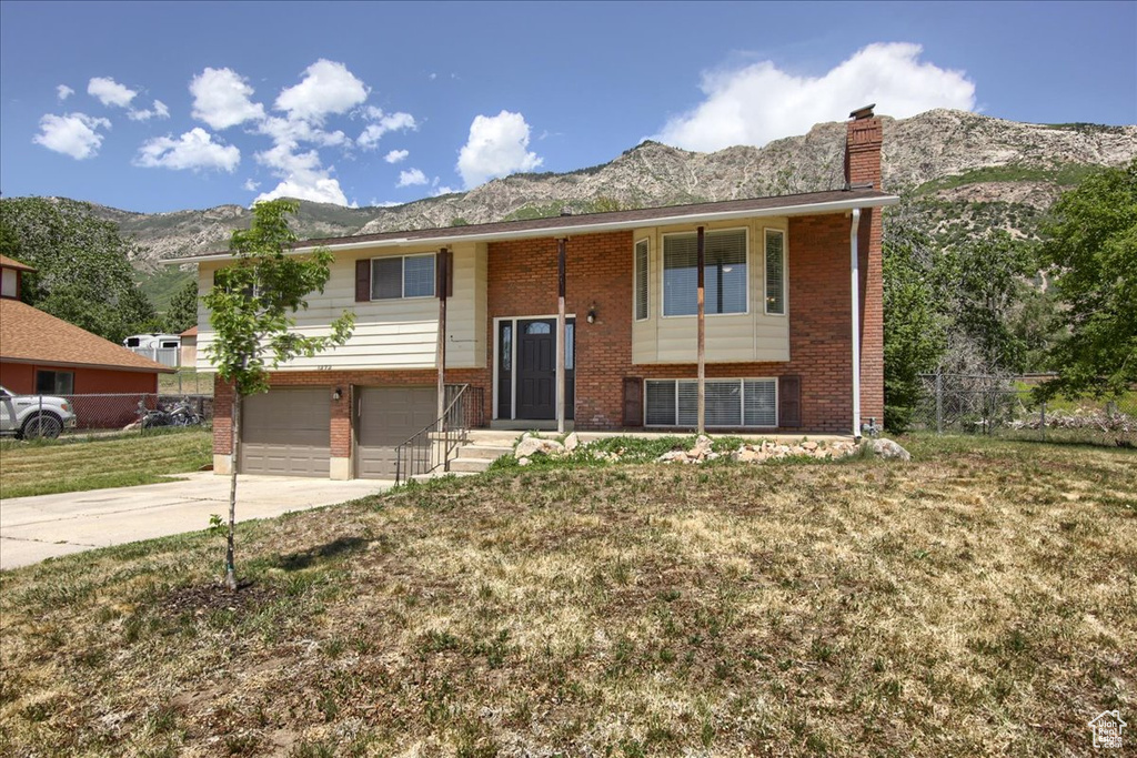 Split foyer home featuring a mountain view, brick siding, concrete driveway, and a garage