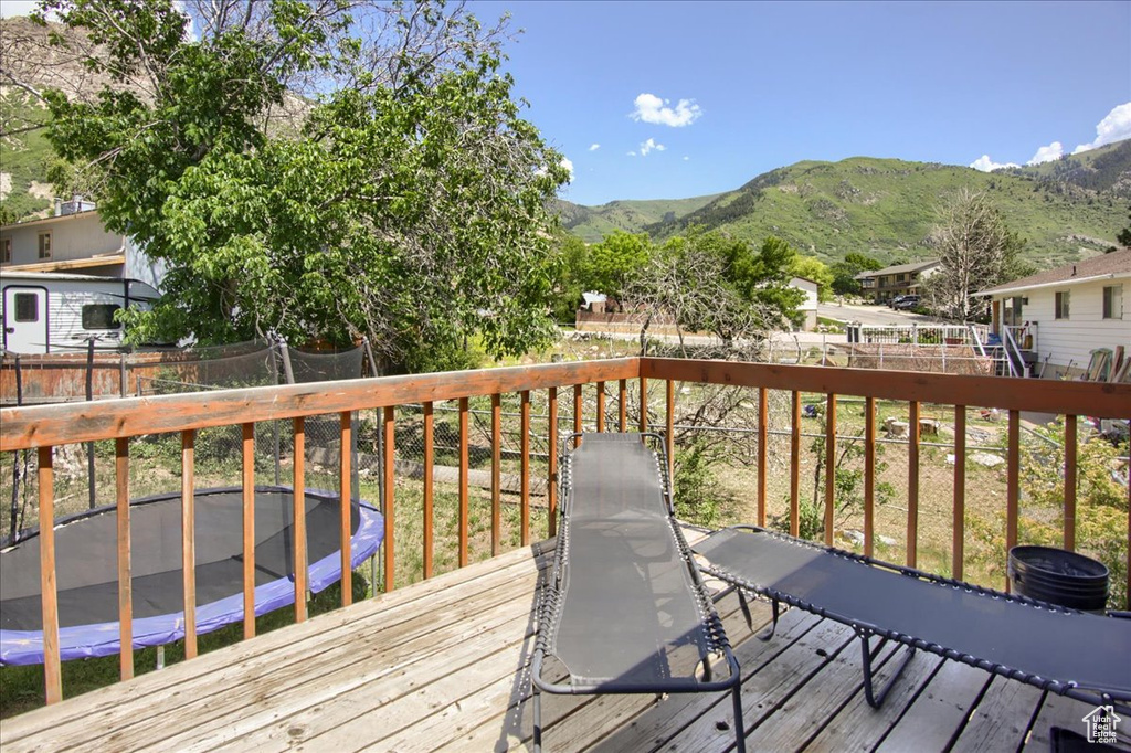 Wooden deck with a trampoline, a fenced backyard, and a mountain view