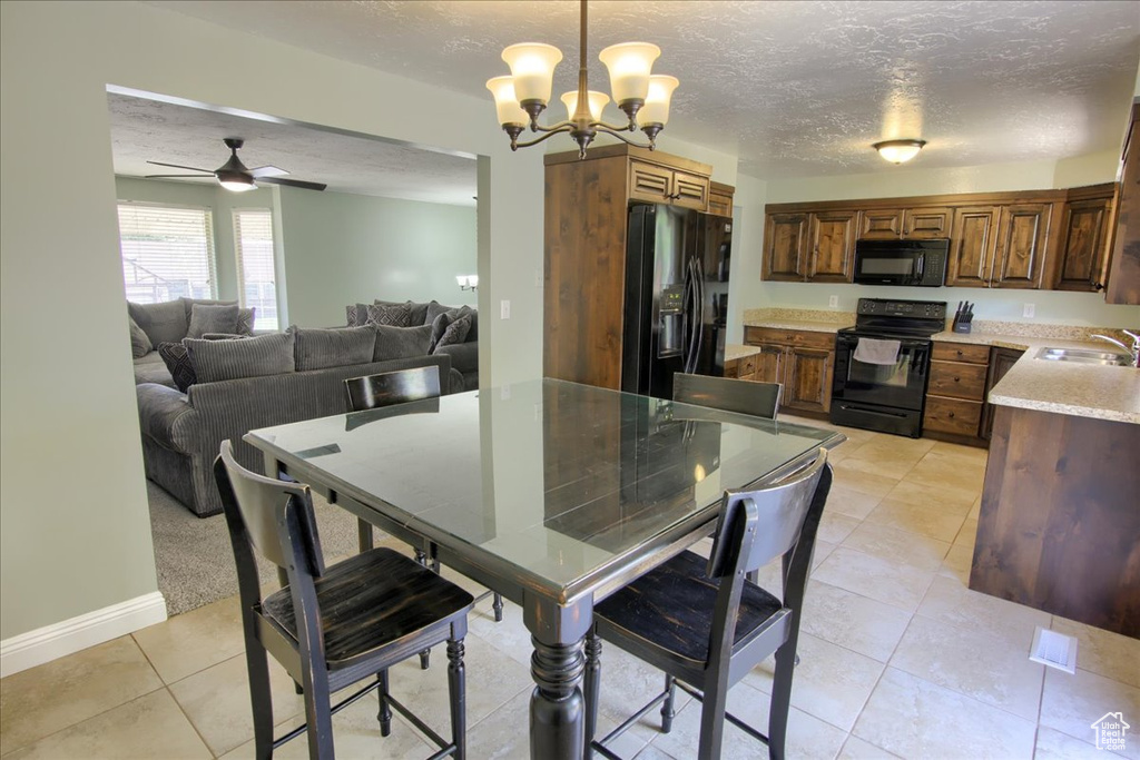 Dining room featuring a chandelier, light tile patterned flooring, a ceiling fan, a textured ceiling, and baseboards