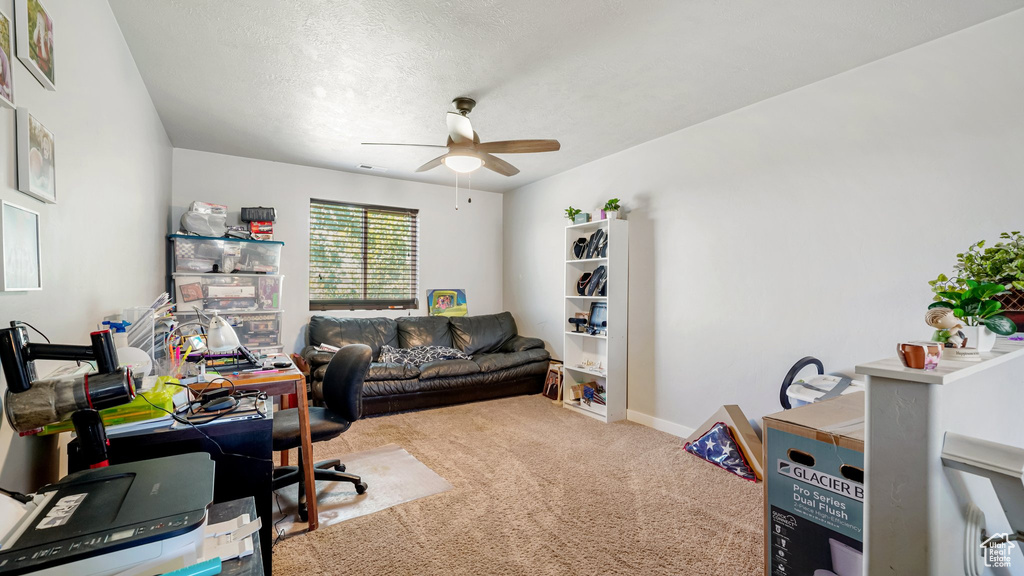 Office with carpet flooring, ceiling fan, baseboards, and a textured ceiling