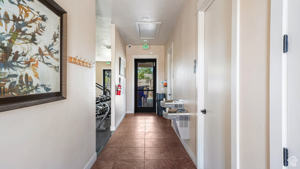 Hallway with attic access, baseboards, and dark tile patterned floors