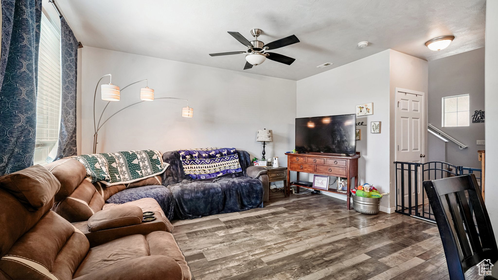 Living area with a ceiling fan, wood finished floors, and baseboards