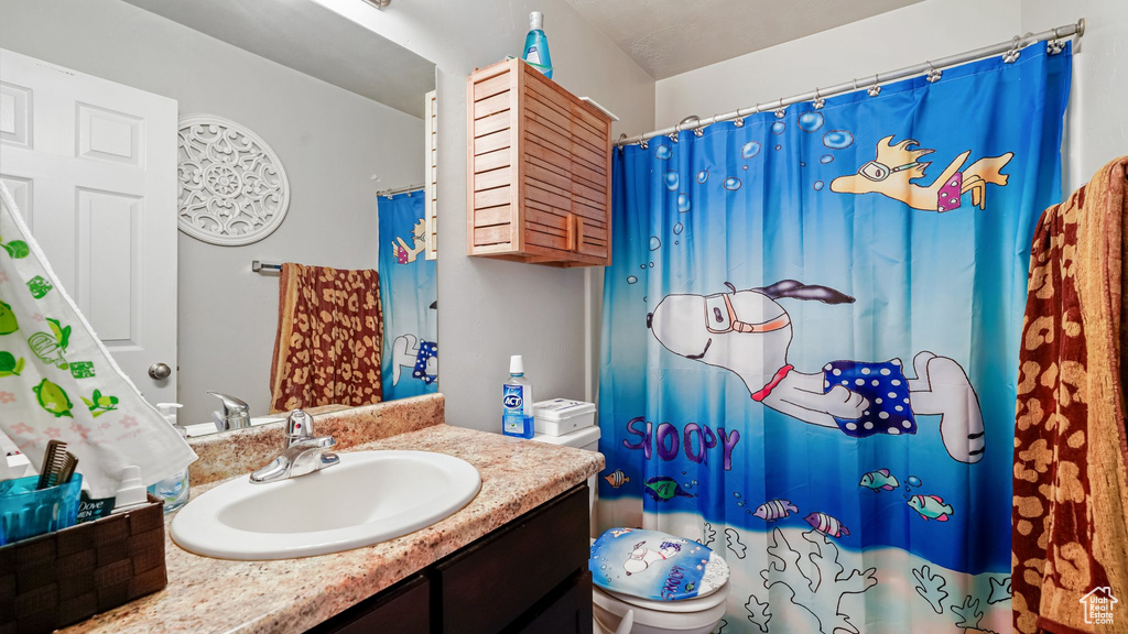 Bathroom with vanity, toilet, and a shower with shower curtain
