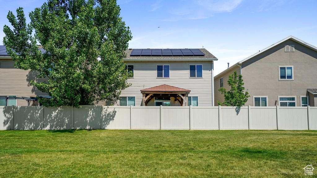 Rear view of house featuring a gazebo, solar panels, and roof with shingles