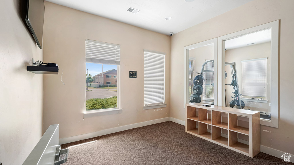Foyer entrance with dark colored carpet and baseboards