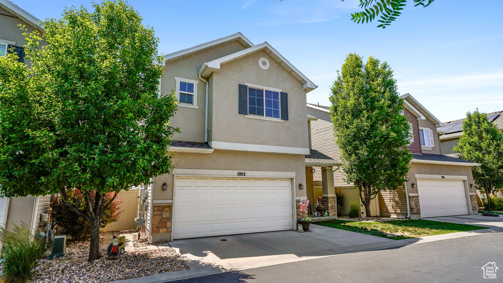 View of front of home featuring stone siding, stucco siding, and a garage