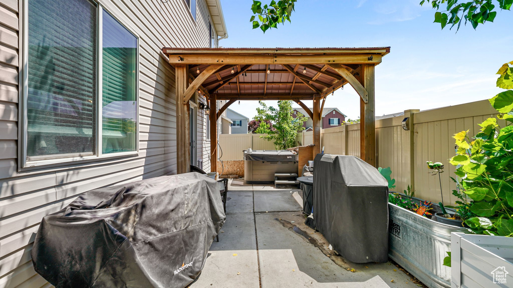 Fenced backyard featuring a hot tub, a gazebo, and a patio