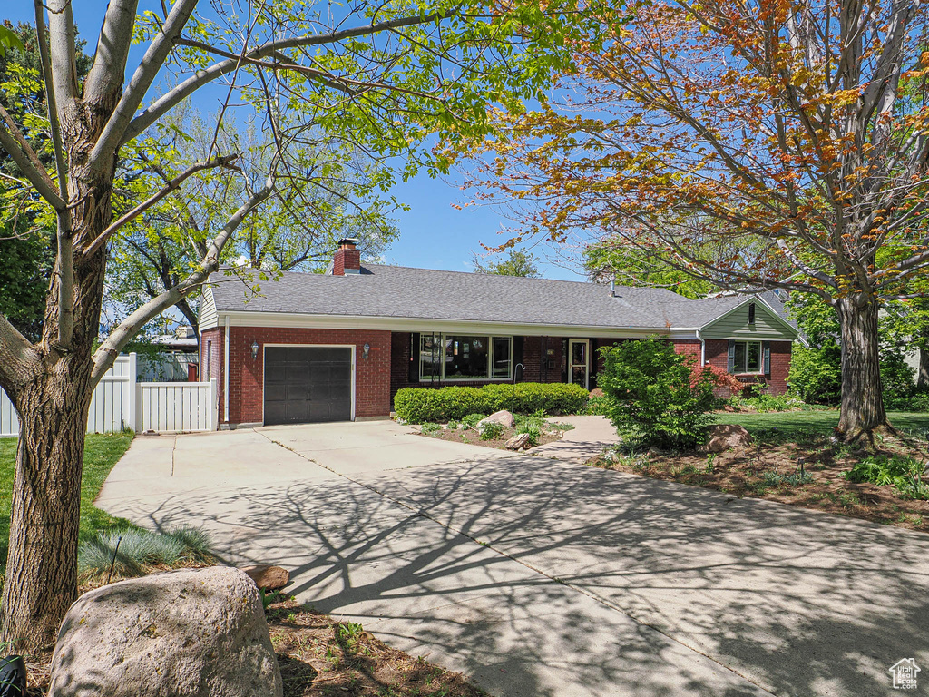 Single story home with brick siding, concrete driveway, a garage, a chimney, and roof with shingles