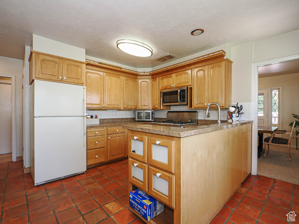 Kitchen featuring freestanding refrigerator, stainless steel microwave, and range
