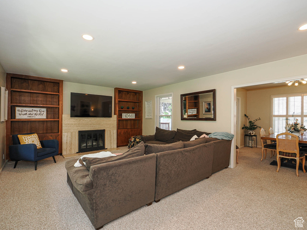 Living room featuring light colored carpet, a glass covered fireplace, and recessed lighting