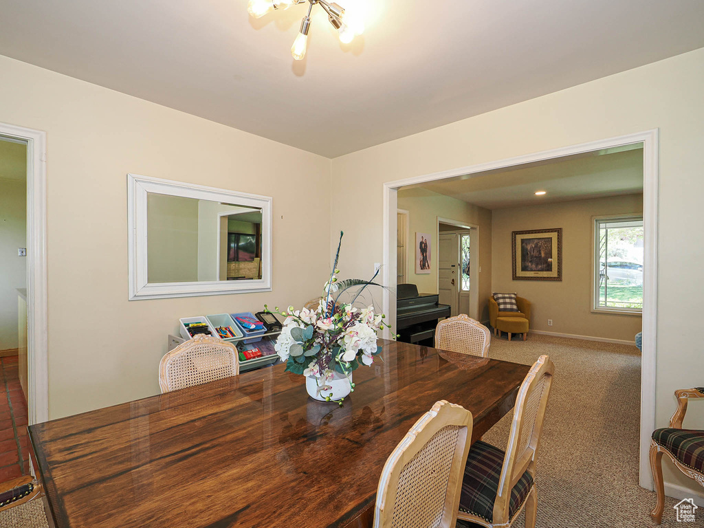 Carpeted dining area with baseboards and a chandelier