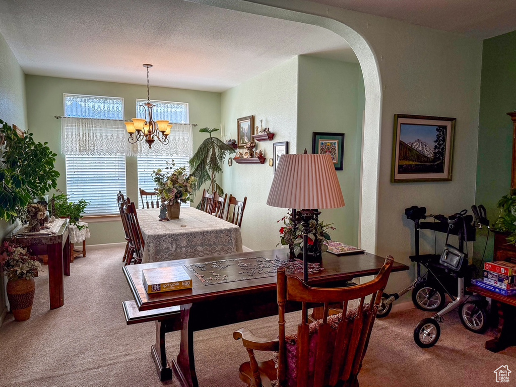 Dining area featuring carpet floors, a chandelier, arched walkways, and baseboards