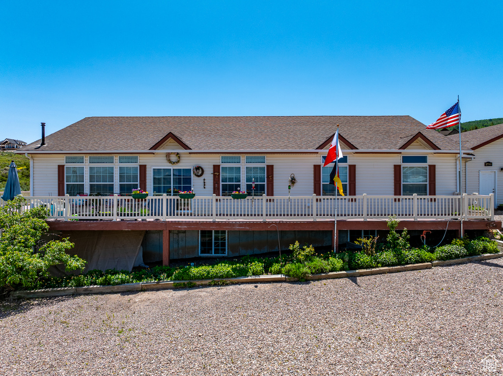 View of front facade featuring a shingled roof and a deck