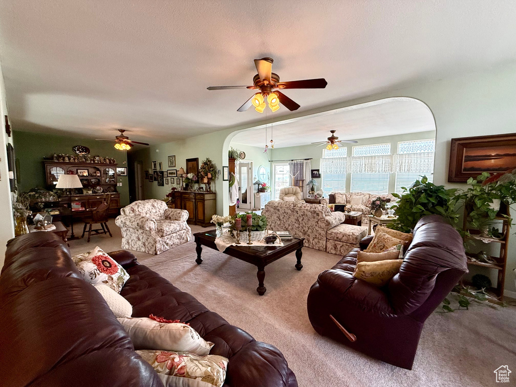Living room featuring a ceiling fan, arched walkways, and light carpet