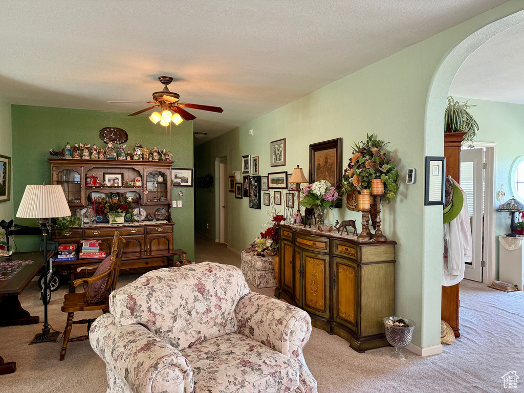 Carpeted living room featuring arched walkways and ceiling fan
