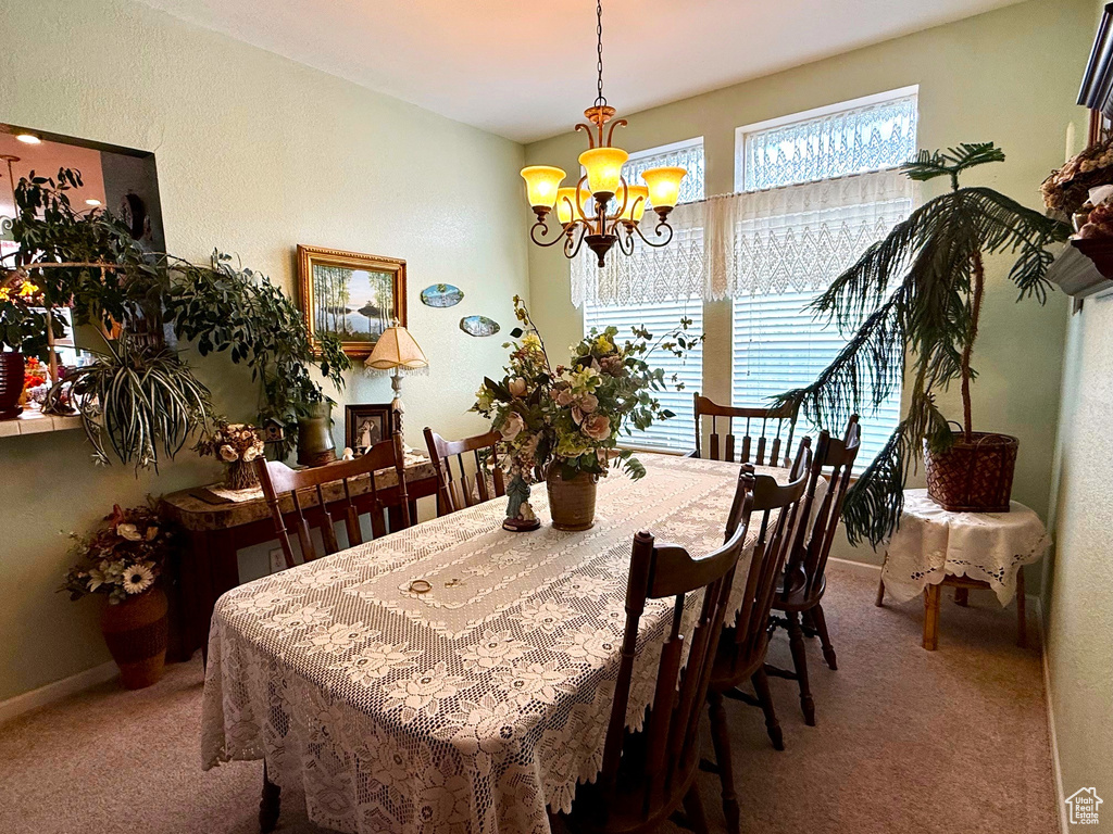 Dining area featuring carpet floors, a chandelier, and baseboards