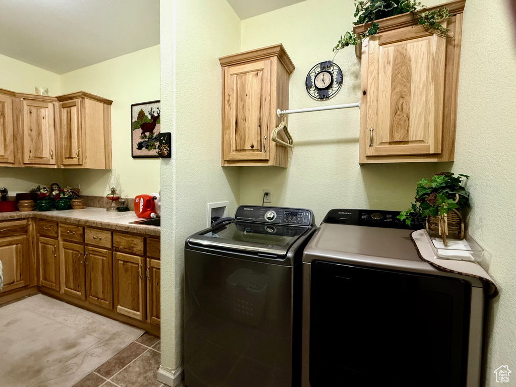Laundry room with washing machine and clothes dryer, cabinet space, and light tile patterned floors