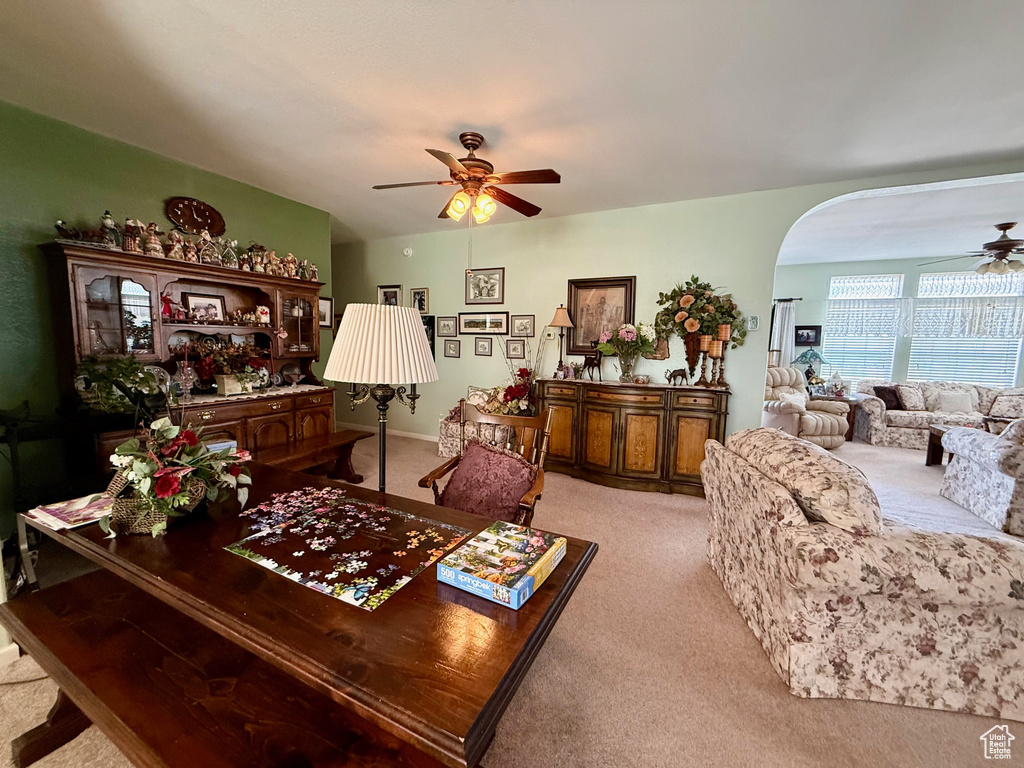 Living room featuring ceiling fan, light carpet, and arched walkways