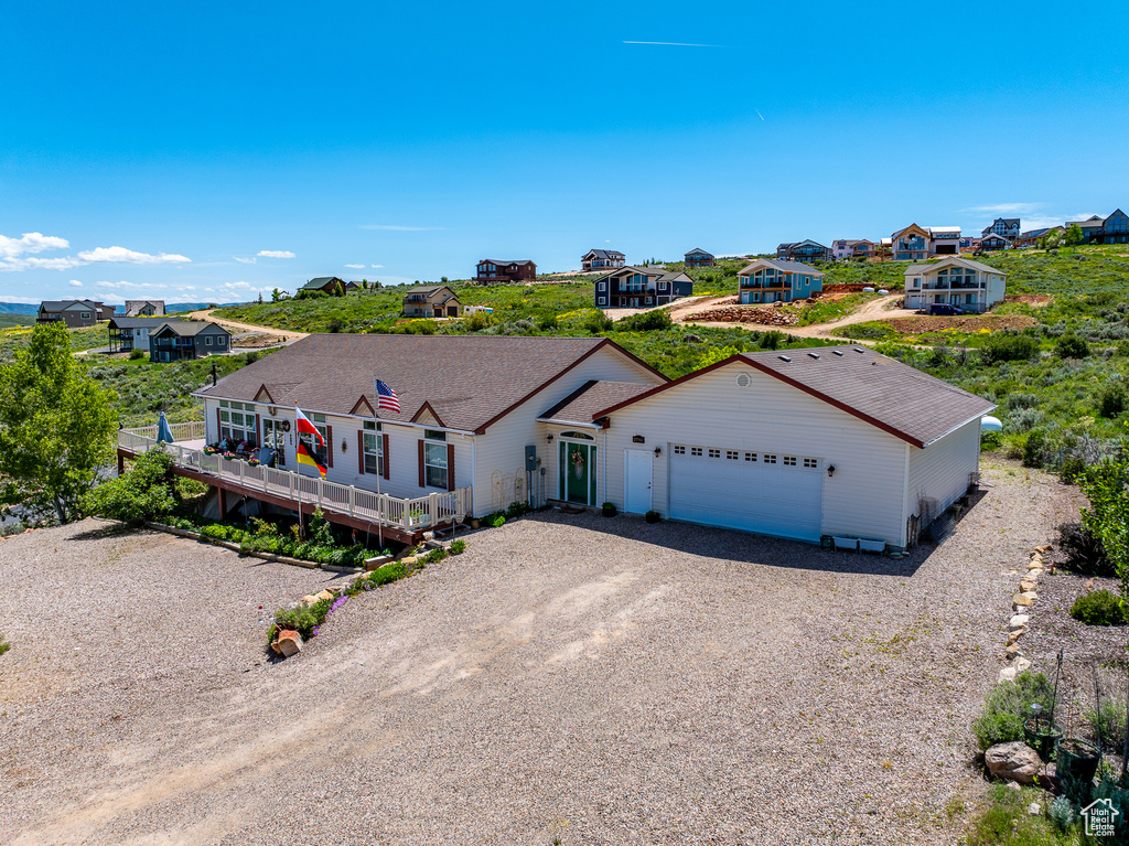 Ranch-style house featuring gravel driveway, an attached garage, a residential view, and a deck