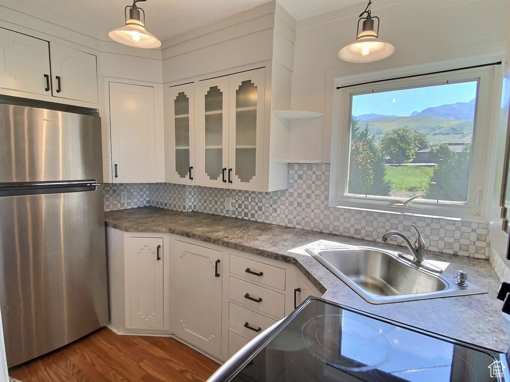 Kitchen with freestanding refrigerator, a sink, white cabinets, and backsplash