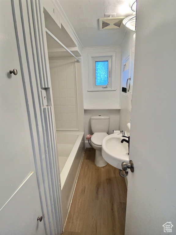 Full bathroom with wood finished floors, a sink, shower / tub combination, and toilet