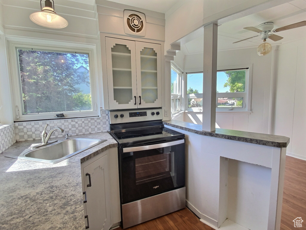 Kitchen featuring stainless steel range with electric cooktop, a sink, plenty of natural light, a peninsula, and ornamental molding