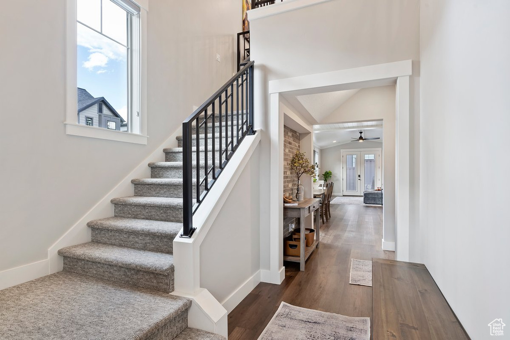 Staircase with wood finished floors, baseboards, ceiling fan, and vaulted ceiling