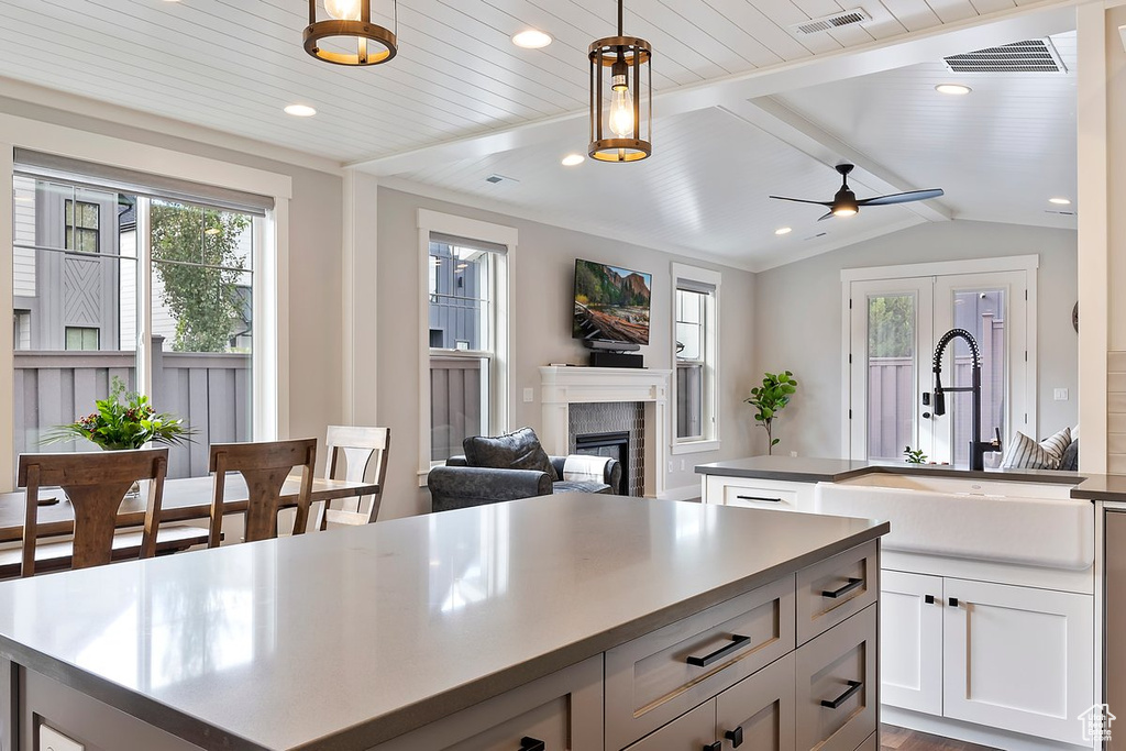 Kitchen featuring a kitchen island, a sink, a brick fireplace, pendant lighting, and ceiling fan