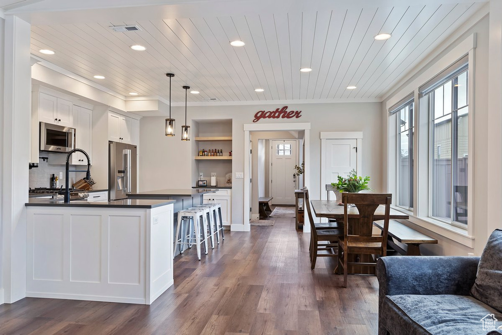 Kitchen featuring stainless steel appliances, dark countertops, open shelves, recessed lighting, and dark wood finished floors