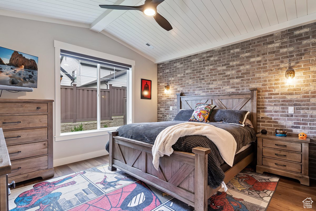 Bedroom with wood finished floors, brick wall, baseboards, and ceiling fan