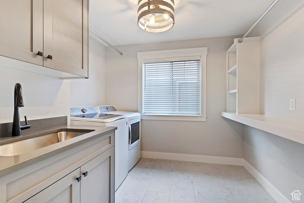 Laundry area featuring washing machine and dryer, cabinet space, and baseboards