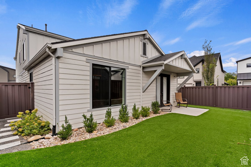 Back of house with board and batten siding and a patio