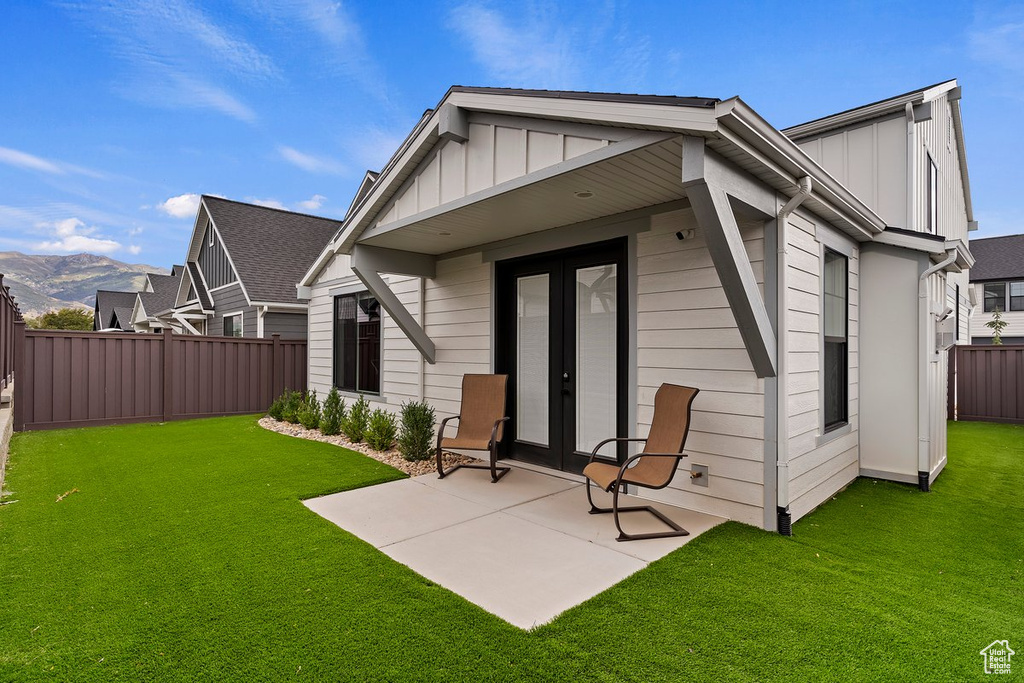 Back of house featuring board and batten siding, french doors, a patio area, and a mountain view
