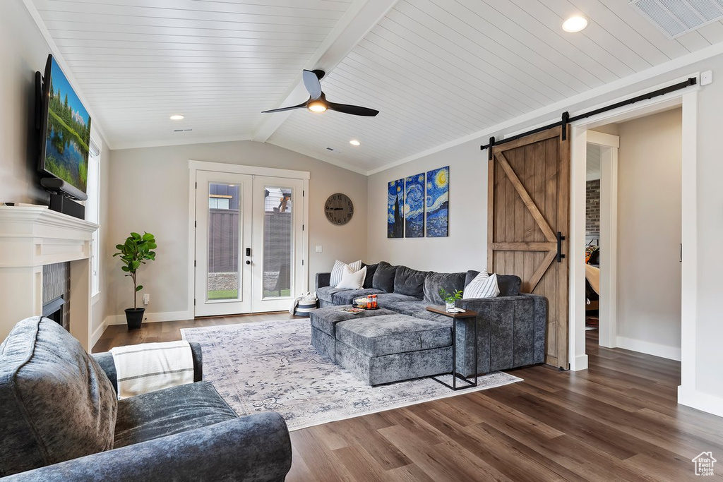 Living area featuring a barn door, wood finished floors, a ceiling fan, baseboards, and a tile fireplace