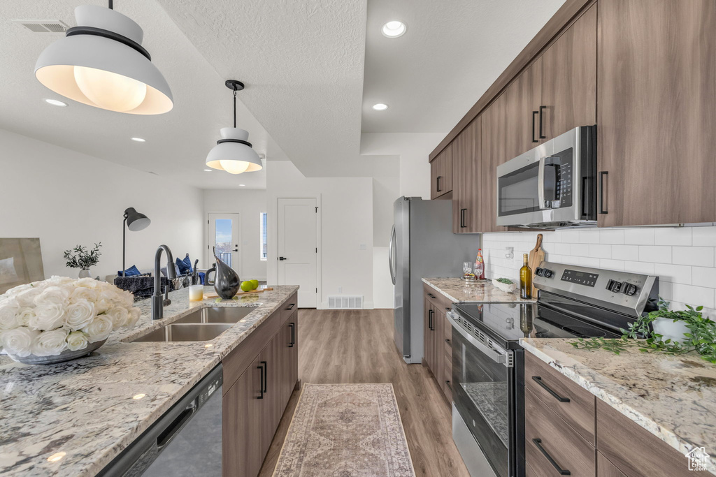 Kitchen featuring appliances with stainless steel finishes, a sink, light wood-type flooring, tasteful backsplash, and recessed lighting