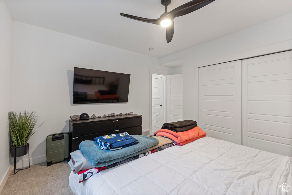 Carpeted bedroom featuring baseboards, a closet, and a ceiling fan