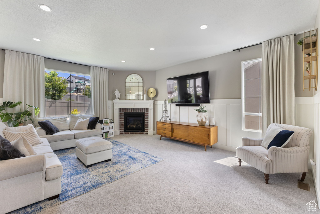 Living room featuring carpet, recessed lighting, wainscoting, a fireplace, and a decorative wall