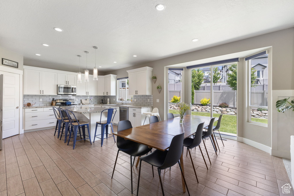 Dining room with light wood-style flooring and recessed lighting