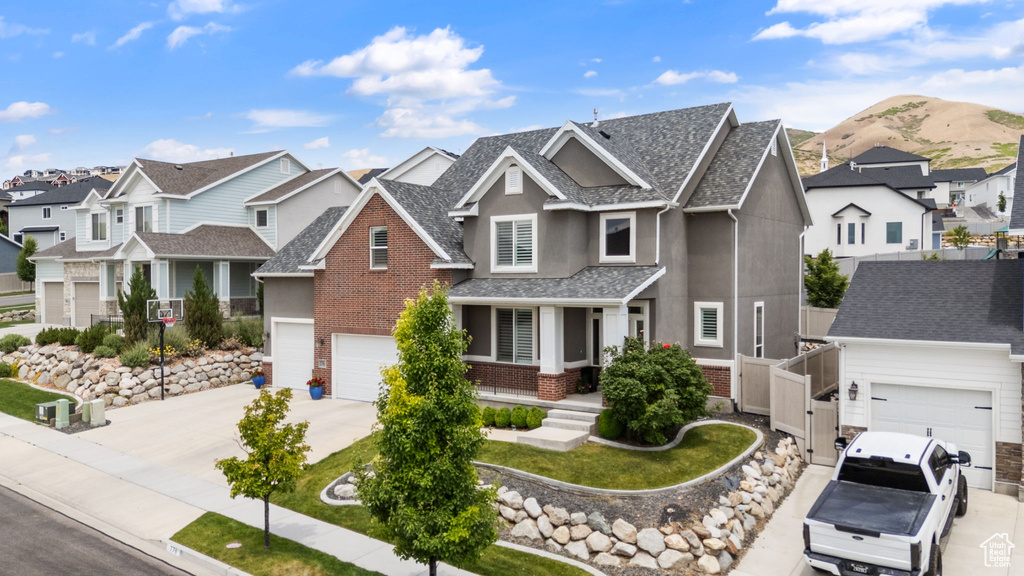 Craftsman-style home featuring a residential view, concrete driveway, stucco siding, a shingled roof, and brick siding