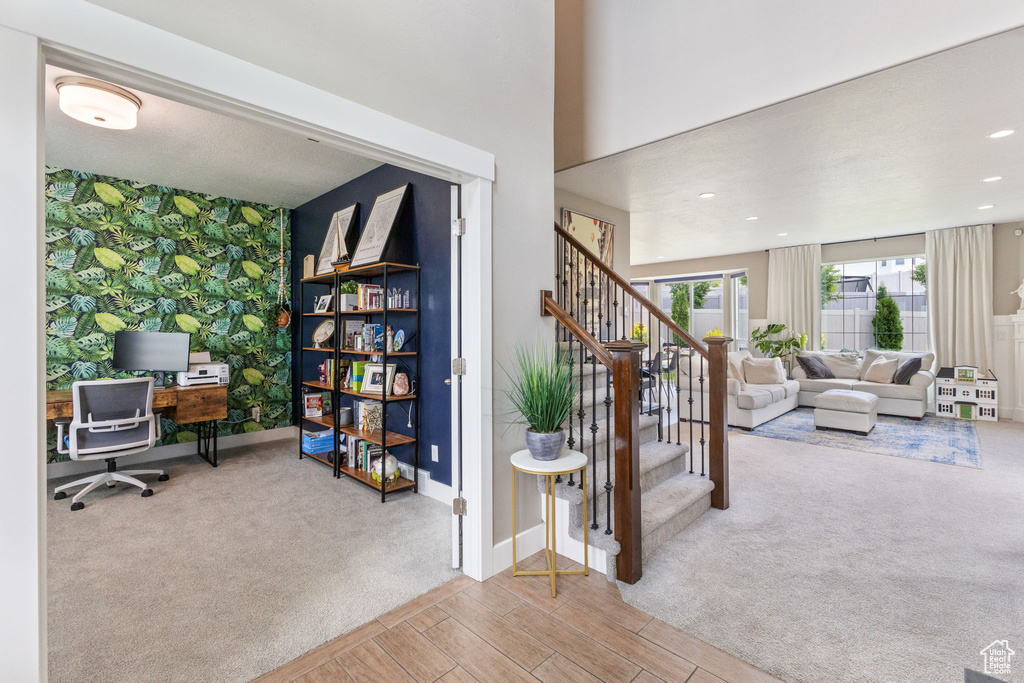 Carpeted office space featuring an accent wall, baseboards, recessed lighting, wood finished floors, and wallpapered walls