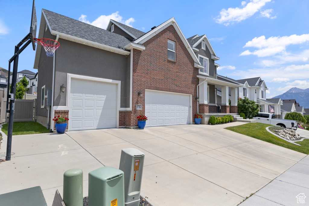 View of property exterior featuring driveway, brick siding, a gate, and a residential view