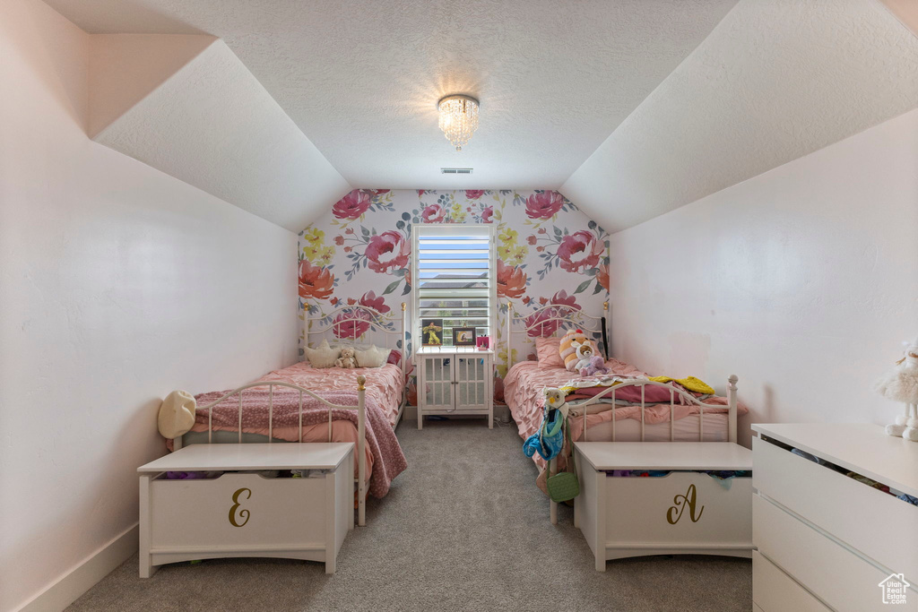 Bedroom with vaulted ceiling, light colored carpet, a textured ceiling, and wallpapered walls