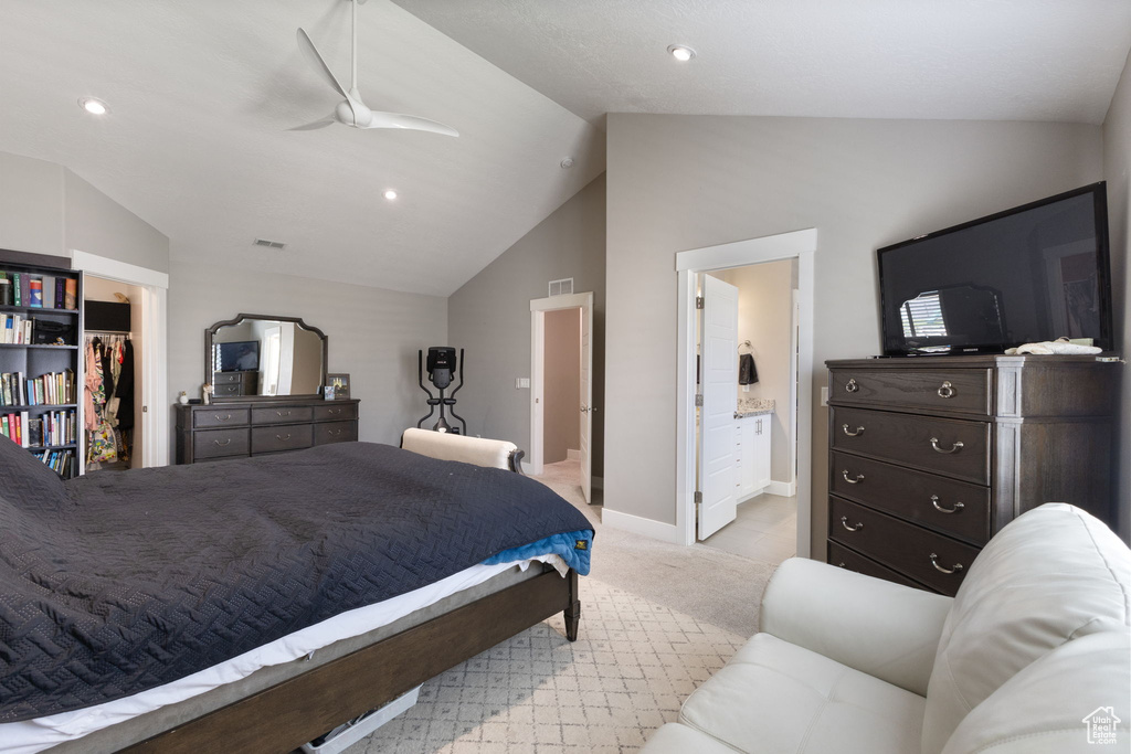 Bedroom with vaulted ceiling, light colored carpet, baseboards, a spacious closet, and ensuite bathroom
