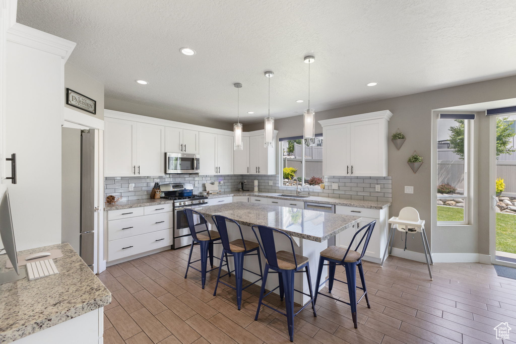 Kitchen with appliances with stainless steel finishes, backsplash, a breakfast bar area, healthy amount of natural light, and recessed lighting