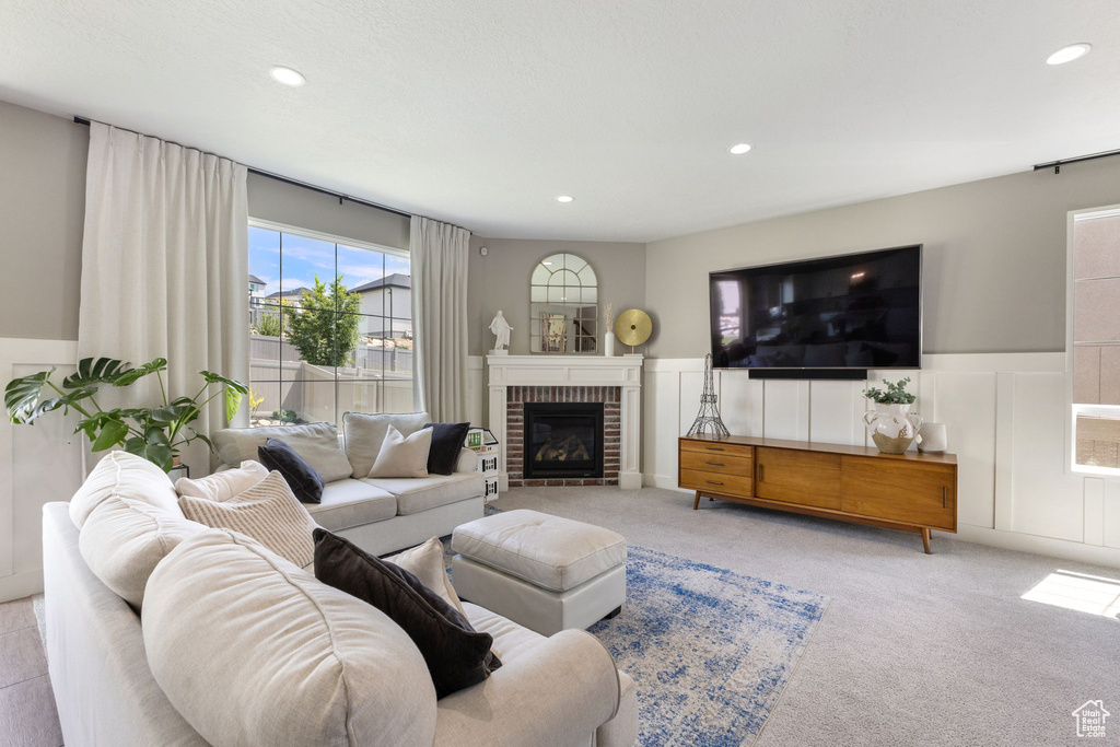 Carpeted living area featuring a wainscoted wall, recessed lighting, a brick fireplace, and a decorative wall