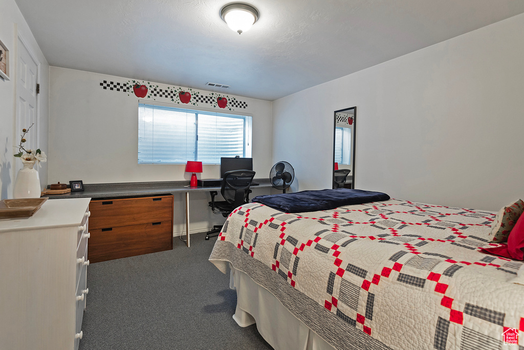 Bedroom with dark colored carpet and an office area
