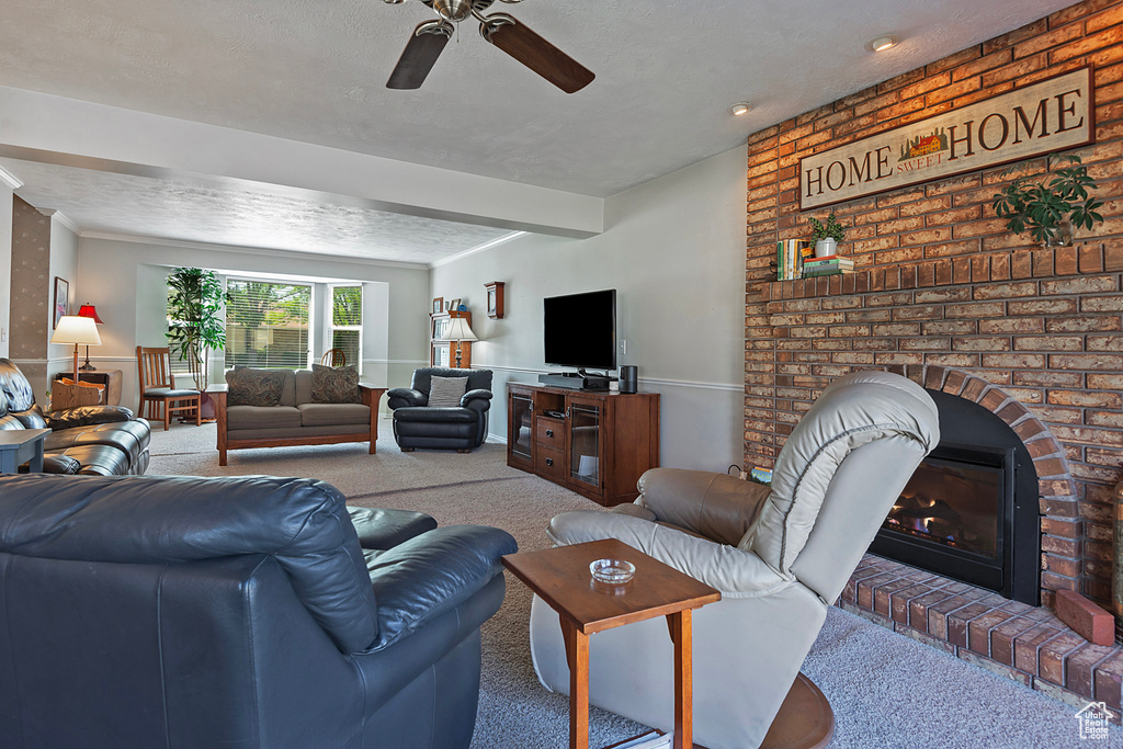 Living room featuring carpet, a ceiling fan, and a brick fireplace