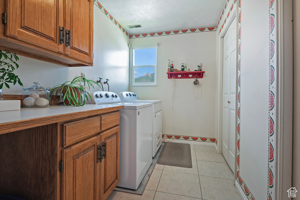 Laundry room with cabinet space, separate washer and dryer, and light tile patterned floors