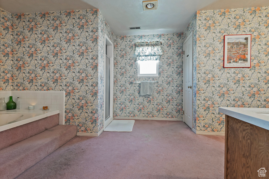 Full bathroom with wallpapered walls, vanity, a garden tub, baseboards, and carpet